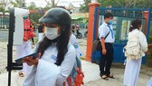 Học sinh trường THPT Giồng Riềng (tỉnh Kiên Giang) rửa tay sát khuẩn và đo thân nhiệt trước khi vào lớp (ảnh minh họa). Ảnh: Q.BÌNH
