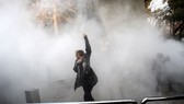 A woman raises her fist amid tear gas at the University of Tehran during a protest on December 30, 2017. – AFP/VNA Photo
