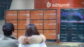 Two people read tables displayed at Bithumb, the largest cryptocurrency exchange in South Korea, in central Seoul on Jan. 11, 2018. (Yonhap)