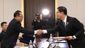 South Korean and North Korean chief delegates shake hands after agreeing at talks on Jan. 17, 2018, to march together under a unified flag at the opening ceremony of the PyeongChang Olympics. (Yonhap)