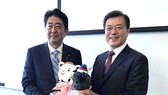 The file photo, taken Sept. 7, 2017, shows South Korean President Moon Jae-in (R) offering the mascots of the 2018 PyeongChang Winter Olympic Games to Japanese Prime Minister Shinzo Abe before the start of their bilateral summit on the sidelines of a regi