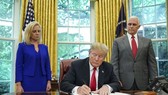US President Donald Trump -- flanked by Homeland Security Secretary Kirstjen Nielsen (left) and Vice President Mike Pence -- signs an executive order to end family separations at the border.—AFP/VNA Photo