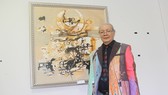 Họa sĩ Uyên Huy bên tác phẩm của mình tại triển lãm