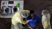 Nhân viên y tế lấy mẫu xét nghiệm Covid-19 cho người dân tại Singapore. Ảnh: AFP/TTXVN