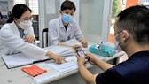 Các bác sĩ đang khám, tư vấn cho người dân tại Trạm y tế phường Hiệp Thành, quận 12. Ảnh: QUANG HUY