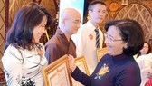 Ms.Than Thi Thu, Head of the Department of Propaganda & Education of HCMC Party Committee (R ) offers certificates of merit to individuals and organizations at the ceremony. (Photo: Sggp)