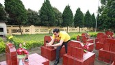 A Vietnam Post staff member takes pictures of a martyr’s tomb while collecting data for the web portal (Photo: VNA)