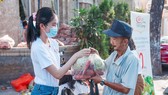 The first runner-up of Miss Vietnam 2020, Pham Ngoc Phuong Anh presents agricultural products to a person. (Photo: SGGP)