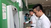 Office workers withdraw money from an ATM. (Photo: VNA)