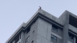 Người đàn ông ngồi cheo leo trên nóc tòa chung cư liên tục la hét