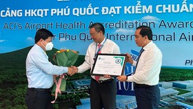 Ông Tống Phước Trường, Bí thư Thành uỷ Phú Quốc (bìa trái) và ông Huỳnh Quang Hưng, Chủ tịch UBND TP Phú Quốc (bìa phải) trao hoa và giấy chứng nhận cho đại diện Cảng HKQT Phú Quốc