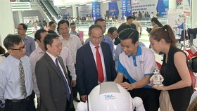 HCMC leaders look at AI products displayed at an exhibition held on the "Day for AI and IT Enterprises" event recently in HCMC. (Photo: VNA/VNS)