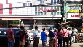 Người dân xếp hàng trước một chi nhánh ngân hàng ở Yangon để chờ rút tiền. Ảnh: Reuters.