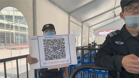 Nhân viên bảo vệ cầm tấm biển có mã QR để du khách quét và tải xuống ứng dụng tại lối vào của Trung tâm Triển lãm và Hội nghị Thâm Quyến vào 12-4-2021. Ảnh: Yujie Xue/SCMP
