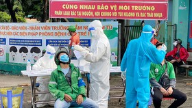 Lấy mẫu xét nghiệm Covid-19 nhân viên giao hàng tại các trạm y tế lưu động. Ảnh: CAO THĂNG