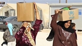 Người tị nạn Syria tại trại tị nạn Zaatari, thành phố Mafraq, Jordan, giáp biên giới Syria nhận hàng viện trợ của Liên hiệp quốc ngày 22-10-2012. Ảnh: REUTERS