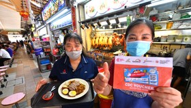Người dân Singapore dùng phiếu thưởng e-voucher để mua hàng