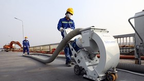Bắn bi tạo nhám đến độ nhám 0,3 mm trên mặt cầu Thăng Long. (Ảnh: Huy Hùng/TTXVN)