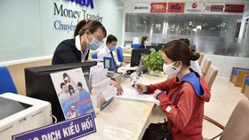 Nhận kiều hối tại một ngân hàng trên đường Nguyễn Thị Minh Khai, Q.3, TP.HCM - Ảnh: NGỌC PHƯỢNG