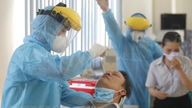 Các y bác sỹ Trung tâm y tế Quận 7 thực hiện xét nghiệm sàng lọc COVID-19 ngẫu nhiên cho công nhân tại Công ty TNHH Kim may Organ Việt Nam. (Ảnh: Thanh Vũ/TTXVN)