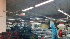 Nhân viên y tế phun khử khuẩn khu vực sản xuất của doanh nghiệp “3 tại chỗ” - Ảnh: VĂN HIỀN