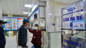 Nhân viên Bến xe Giáp Bát kiểm tra thân nhiệt tất cả hành khách vào bến. (Ảnh: Hoàng Hiếu/TTXVN)