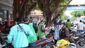 Nhiều tài xế xe công nghệ cùng shipper bị mời về phường vì vi phạm phòng chống dịch Covid-19. Ảnh: CHÍ THẠCH