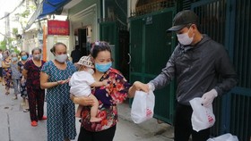 Anh Huỳnh Duy Quang Tố, Tổ phó Tổ dân phố 27, khu phố 3, phường 11 (quận Phú Nhuận, TPHCM) phát lương thực thiết yếu cho người dân có hoàn cảnh khó khăn trong tổ