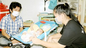 Từ ngày mẹ mất, Nguyễn Phương Quỳnh Như (quận Tân Bình) thay mẹ lo cho em mới hơn 2 tháng tuổi. Ảnh: THÁI PHƯƠNG