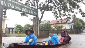 Người dân huyện Quảng Điền, tỉnh Thừa Thiên - Huế di chuyển trên đường ngập lụt, chiều 17-10. Ảnh: VĂN THẮNG
