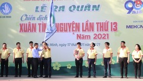 Head of the HCMC Party Committee's Mass Mobilization Commission Nguyen Huu Hiep (L) hands over a flag to students to kick off the campaign. (Photo: SGGP)