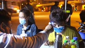 Healthcare workers are measuring the temperature of arrivals at a checkpoint. (Photo: SGGP)
