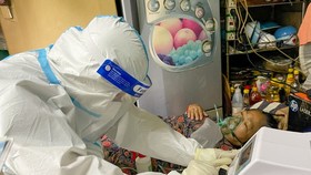 A healthcare worker of the Nguyen Cu Trinh Ward is taking care a Covid-19 patient at home. (Photo: SGGP)