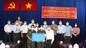 Head of the HCMC Party Committee's Commission for Mass Mobilization Nguyen Huu Hiep (R) presents gifts to Goa Vap District. (Photo: SGGP)