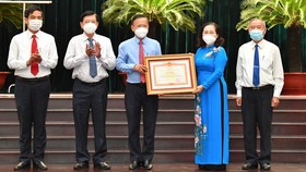 Chairwoman of the HCMC People’s Council, Nguyen Thi Le hands over the Certificate of Merit from the Prime Minister to the HCMC Party Committee's Commission for Mass Mobilization.