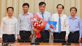 Phó Chủ tịch thường trực UBND TP Lê Thanh Liêm (thứ 2 từ trái sang) trao quyết định cho ông Lê Hòa Bình (giữa). ẢNh: VIỆT DŨNG