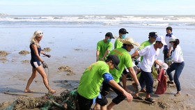 Foreigners and local people join hands to clean Mui Ne beach on July 12 (Photo: VNA)
