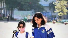Bui Thi Hau walks in the school with the assistance of her friend (Photo: SGGP)