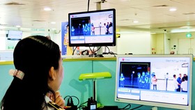 Nhân viên kiểm tra thân nhiệt hành khách nhập cảnh vào Sân bay Tân Sơn Nhất