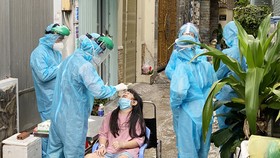 Nhân viên y tế lấy mẫu xét nghiệm SARS-CoV-2 cho người dân sống tại hẻm 415 Nguyễn Văn Công, phường 3, quận Gò Vấp, ngày 27-5-2021. Ảnh: CAO THĂNG