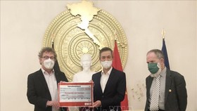  Chủ tịch Đảng Cộng sản Đức Patrik Köbele (trái) và ông Stefan Kühner (phải) trao số tiền quyên góp cho Đại sứ Nguyễn Minh Vũ. Ảnh: TTXVN