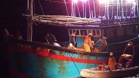 Các nhân viên cứu nạn đưa ngư dân Huỳnh Văn Cương sang tàu cứu nạn bằng xuồng cao su 