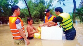 A boy receives food from rescue force in the Mekong Delta (Photo: SGGP)