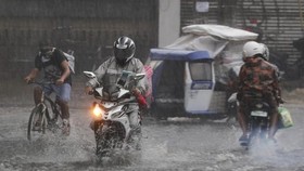 People wearing face masks cross a flooded street during a brief downpour in Quezon city, Philippines Sept. 7, 2020 (Photo: AP)