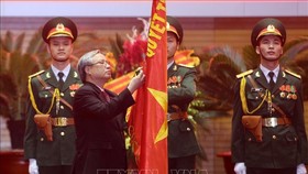 Đồng chí Trần Quốc Vượng, Thường trực Ban Bí thư gắn Huân chương Bảo vệ Tổ quốc hạng Nhất lên lá cờ truyền thống của Tổng cục Chính trị QĐND Việt Nam. Ảnh: TTXVN