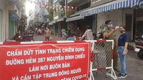 Đo thân nhiệt người dân ra vào khu chợ tự phát  hẻm 287 Nguyễn Đình Chiểu (phường 5 quận 3)