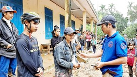 Thầy giáo Nguyễn Trần Vỹ (bìa phải) trao tặng tiền hỗ trợ bà con  xã Trà Leng, Quảng Nam, bị bão số 9 làm hư hại tài sản
