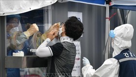 Nhân viên y tế lấy mẫu dịch xét nghiệm COVID-19 cho người dân tại Seoul, Hàn Quốc. Ảnh tư liệu: AFP/TTXVN