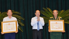 Ủy viên Trung ương Đảng, Phó Bí thư Thường trực Thành ủy TPHCM Tất Thành Cang trao tặng và chúc mừng các đồng chí nhận Huân chương Độc lập hạng Ba. Ảnh: VIỆT DŨNG