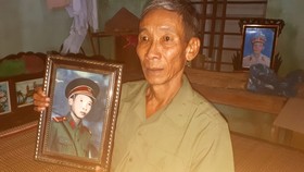 Ông Phạm Văn Bình bên hình ảnh ông chụp thời đi bộ đội